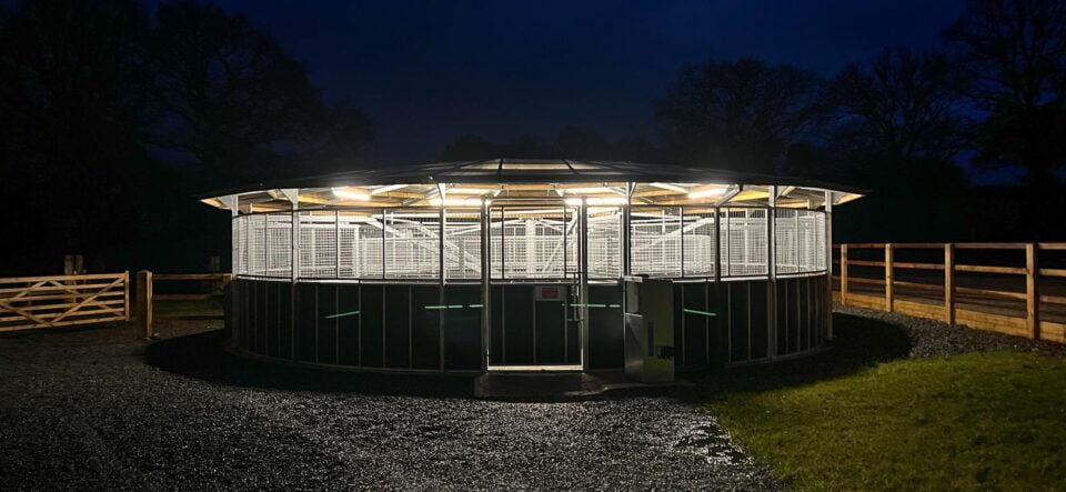 A covered and lit horse walker at night